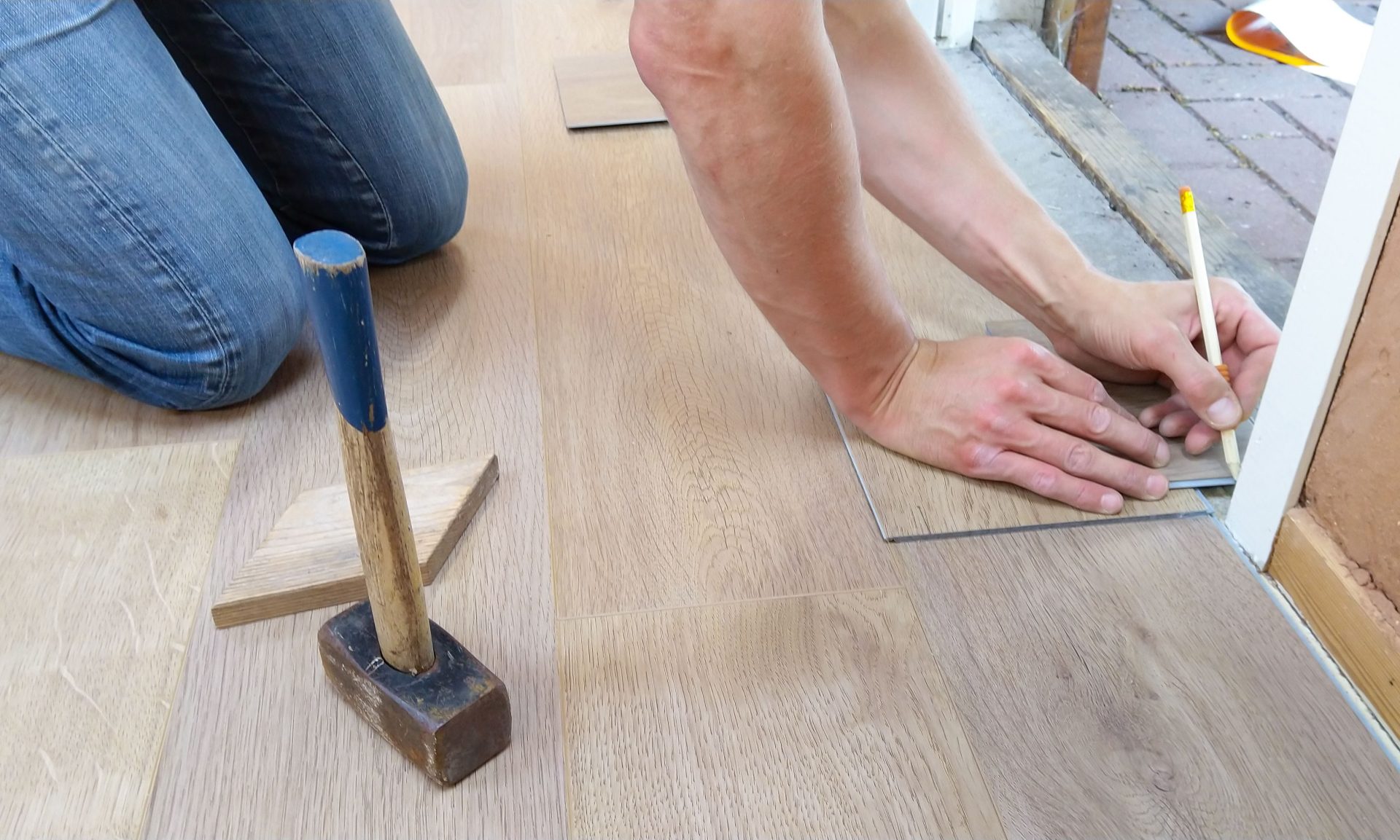 Ein Handwerker misst Holzbodenpaneele sorgfältig aus und markiert sie für eine präzise Verlegung.