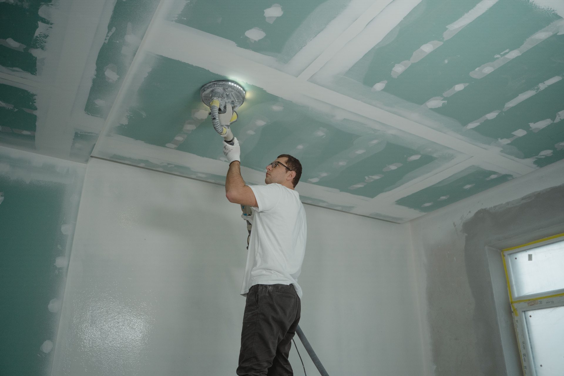 Ein Handwerker poliert fachmännisch eine Zimmerdecke und stellt dabei sein Können bei der Hausrenovierung unter Beweis.