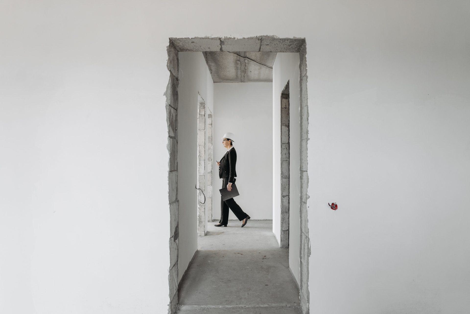 Eine Geschäftsfrau in formeller Kleidung begutachtet eine unfertige Baustelle. Ideal für Themen aus den Bereichen Immobilien und Bauwesen.